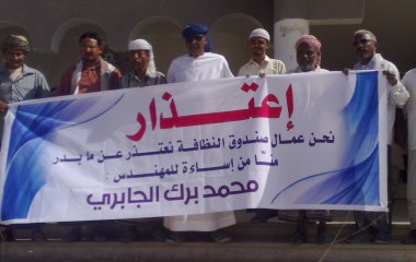 عمال النظافة بسيئون الموقفين عن العمل يرفعون لافتة اعتذار للمدير العام لصندوق النظافة بالوادي